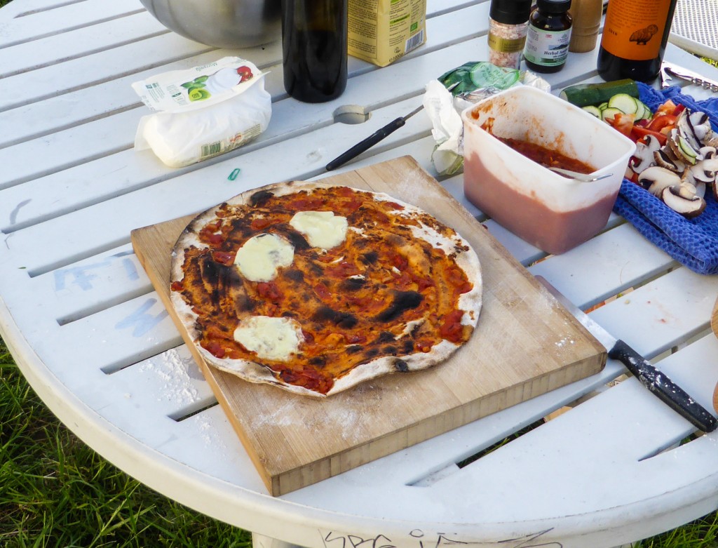 Zwei Minuten später ist sie knusprig durchgebacken, in Kürze in viele Stücke aufgeschnitten, vom Pizzaofen-Bauteam und von Margret, Susanne, Theo, Reto und Willi gekostet und für lecker befunden. 